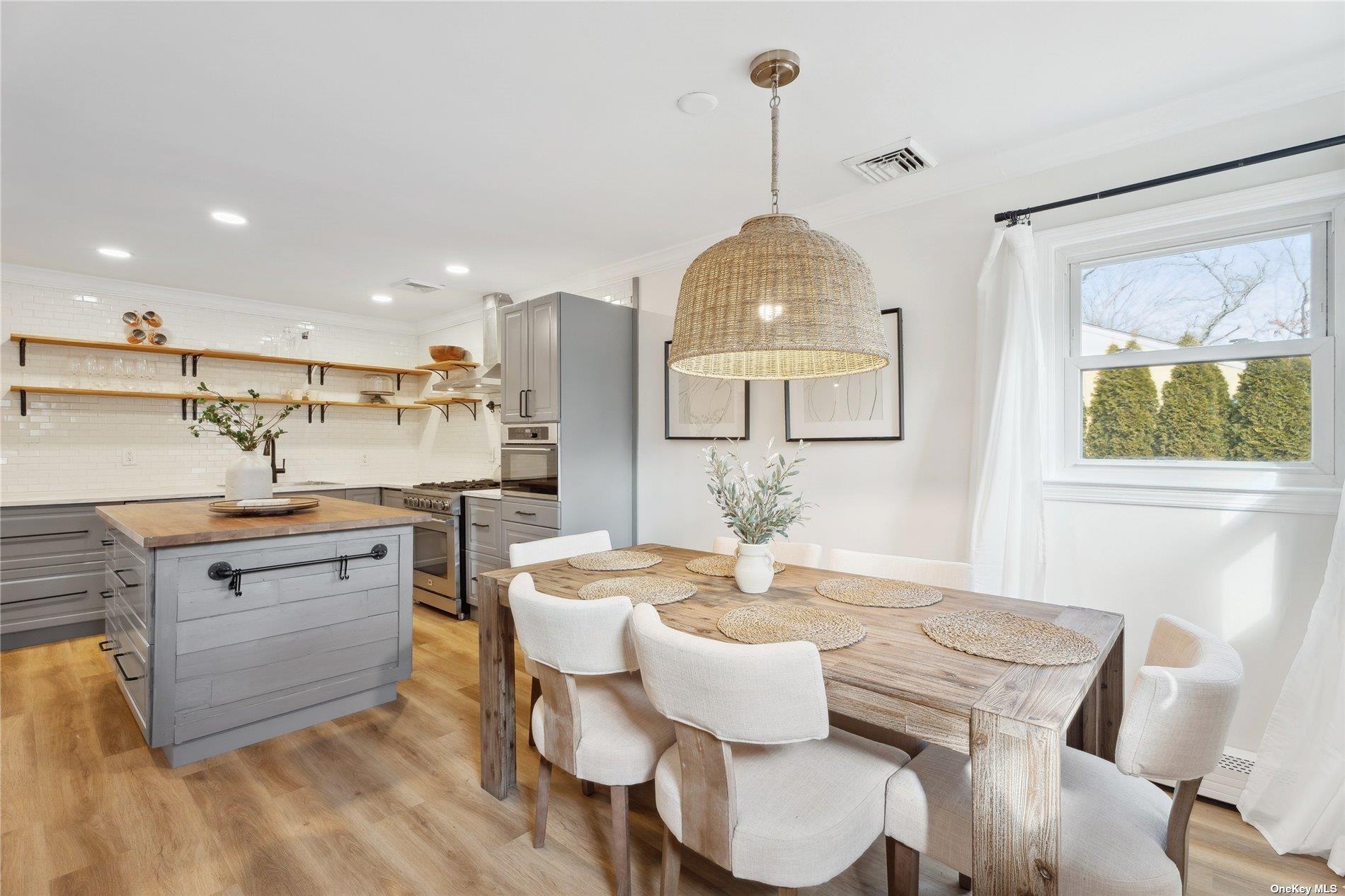 28 Argonne Road West Hampton Bays, NY 11946 - Photo 6 of 24 a kitchen with a dining table chairs and stove