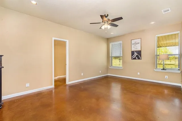 a view of an empty room with window and chandelier fan