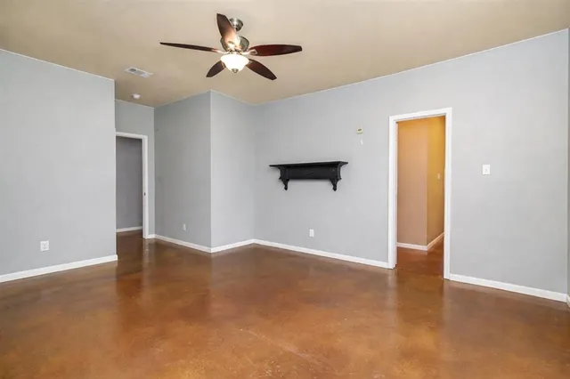 a view of an empty room with window and a ceiling fan