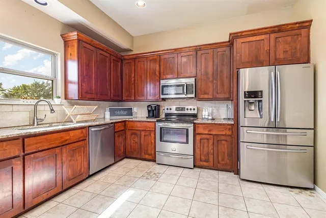 a kitchen with stainless steel appliances granite countertop a refrigerator stove top oven and sink