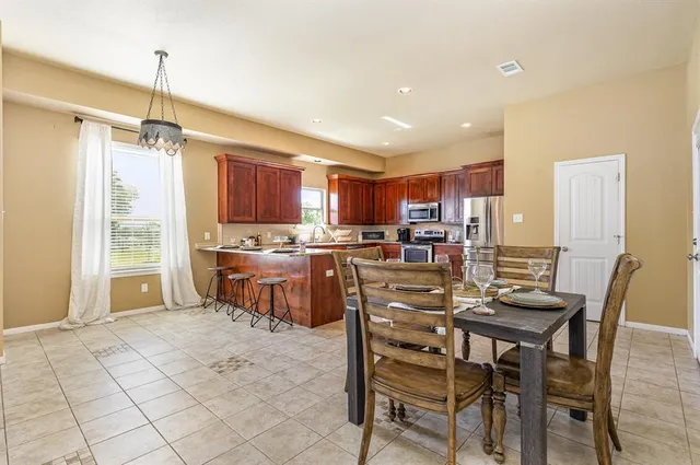 a kitchen with stainless steel appliances kitchen island granite countertop a table chairs and a refrigerator