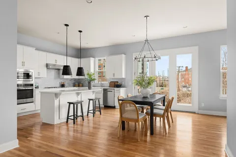 a view of a dining room and livingroom with furniture wooden floor kitchen chandelier