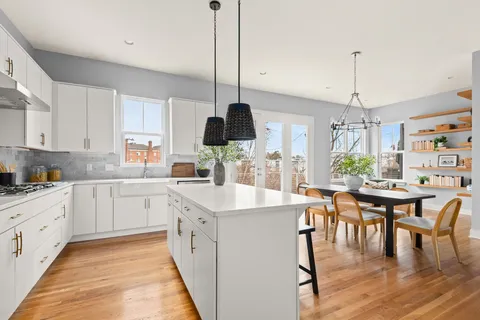 a kitchen with stainless steel appliances granite countertop a kitchen island a stove a sink a dining table and chairs with wooden floor