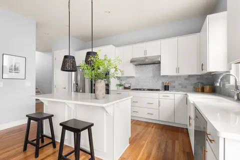 a kitchen with stainless steel appliances kitchen island granite countertop a sink a stove and white cabinets