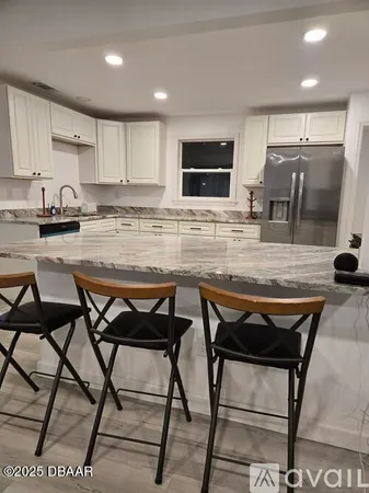 a kitchen with stainless steel appliances kitchen island granite countertop a table chairs sink and cabinets