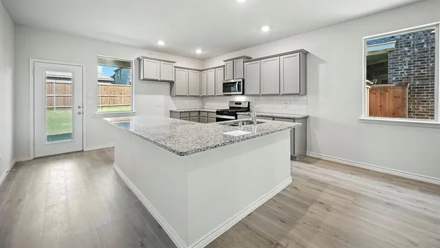 a kitchen with stainless steel appliances granite countertop a stove a sink and a refrigerator