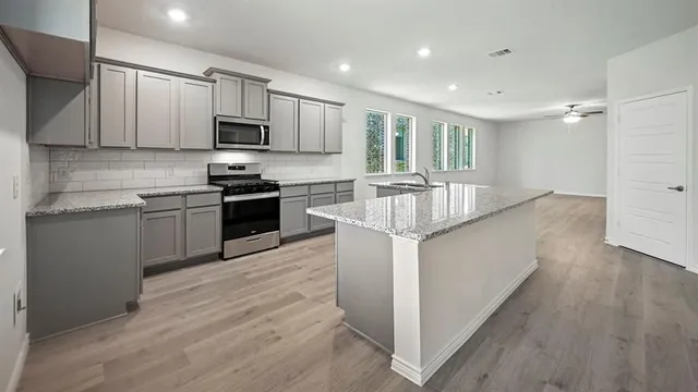 a kitchen with stainless steel appliances granite countertop a stove a sink and a refrigerator