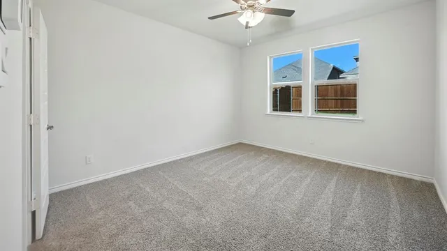 an empty room with a chandelier fan and window