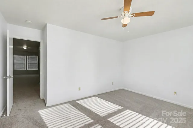 an empty room with a ceiling fan and a window