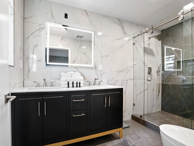 a bathroom with a double vanity sink mirror and shower