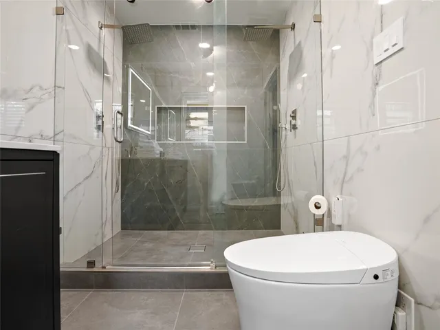 a bathroom with a white toilet and shower