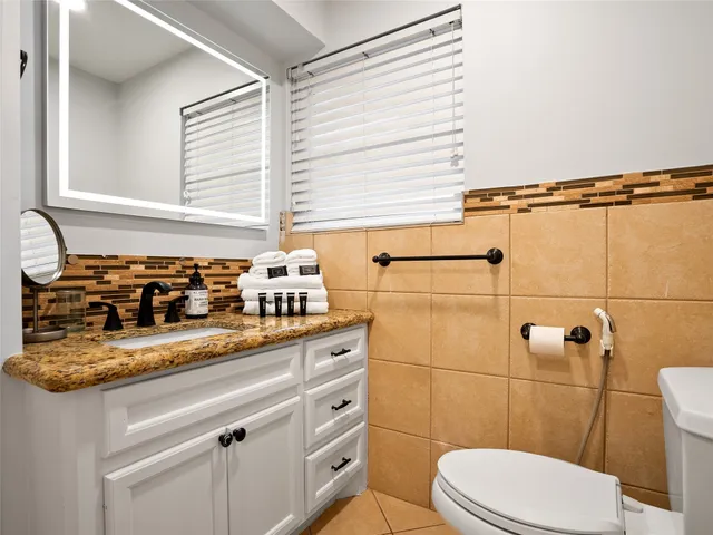a bathroom with a granite countertop sink a toilet and shower