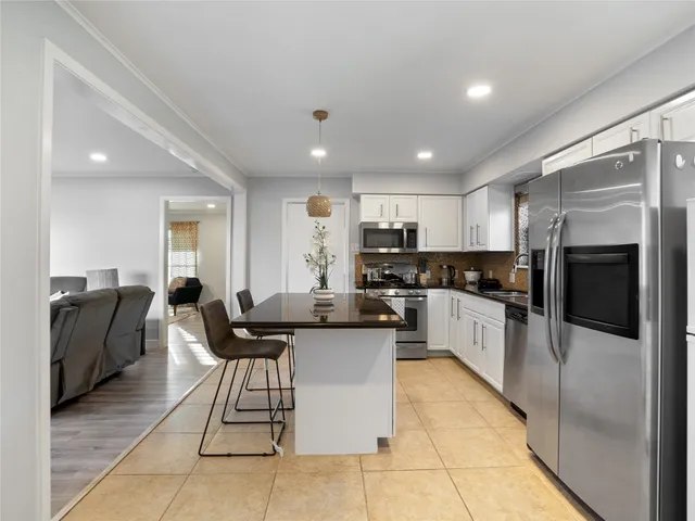 a kitchen with stainless steel appliances kitchen island granite countertop a refrigerator a stove a sink a table and chairs