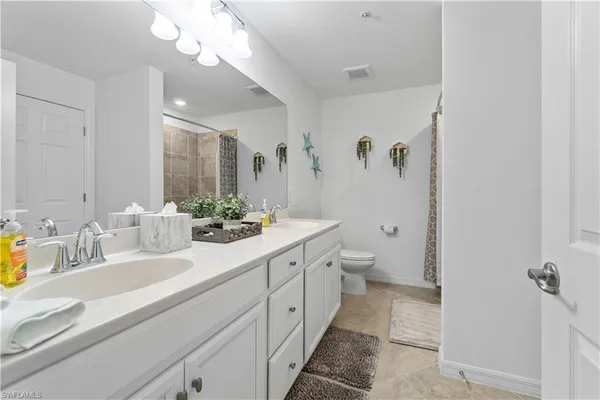 a bathroom with a double vanity sink mirror and toilet