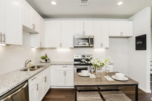 a kitchen with stainless steel appliances kitchen island granite countertop a sink a stove a microwave a refrigerator and cabinets