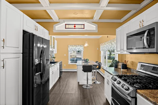 a kitchen with stainless steel appliances granite countertop a stove a refrigerator a sink dishwasher a dining table and chairs with wooden floor