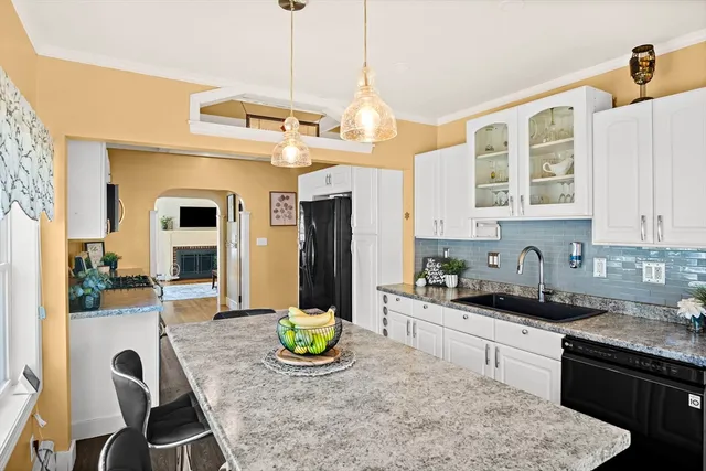 a kitchen with stainless steel appliances granite countertop a stove a refrigerator a sink a dining table and chairs with wooden floor