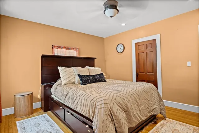 a bedroom with a bed and dresser with wooden floor