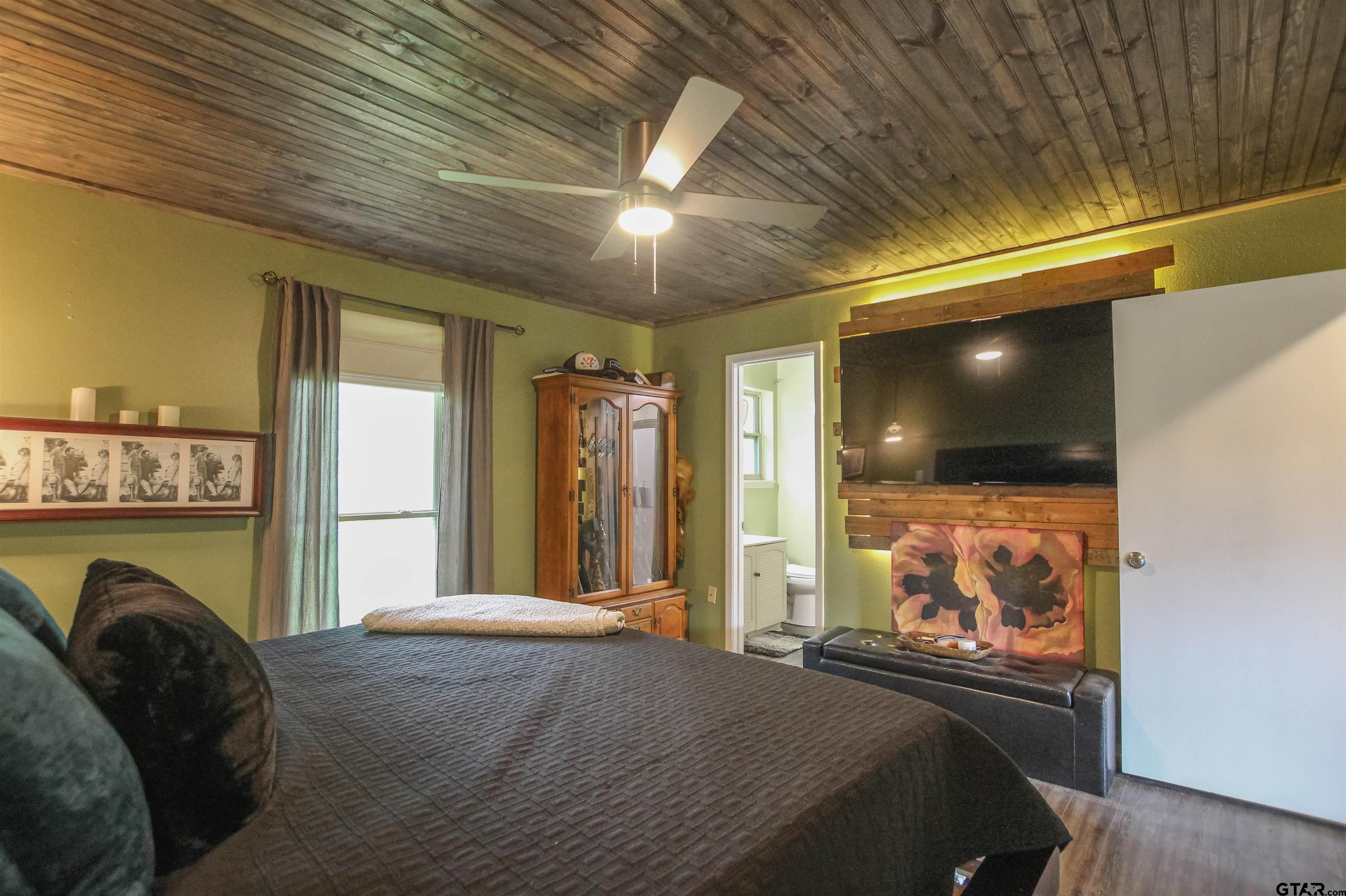 7546 Hill N Dale Road Tyler, TX 75709 - Photo 11 of 24 a bedroom with a bed window and flat screen tv