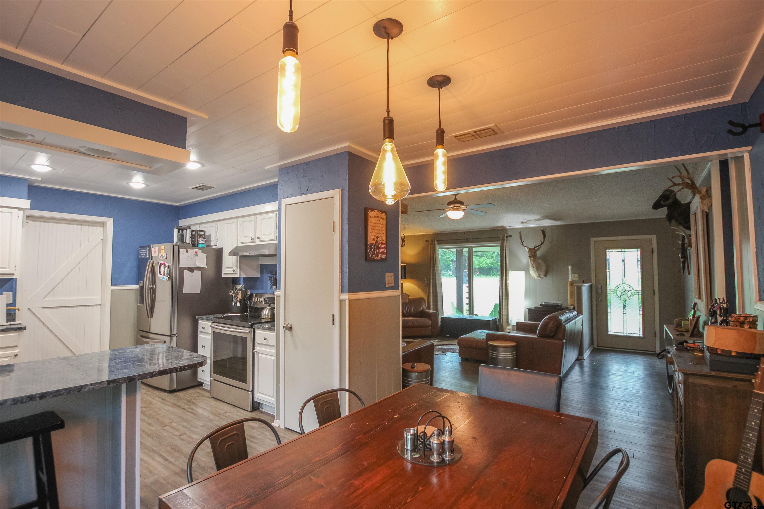 7546 Hill N Dale Road Tyler, TX 75709 - Photo 6 of 24 a view of a dining room and livingroom with furniture wooden floor a rug a fireplace