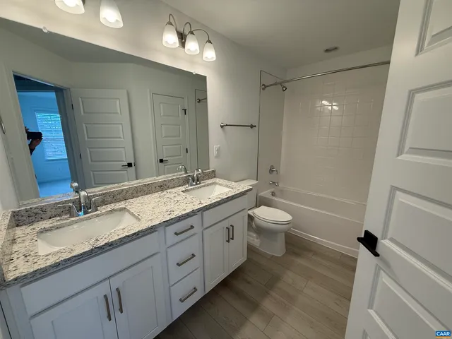 a bathroom with a granite countertop sink toilet a large mirror a bathtub and shower