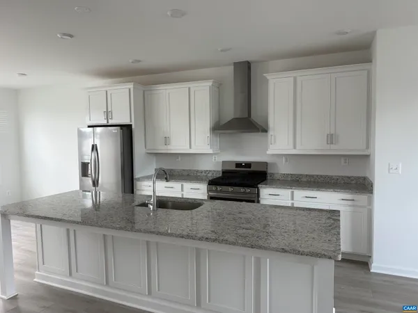 a kitchen with stainless steel appliances granite countertop a sink a stove and a refrigerator