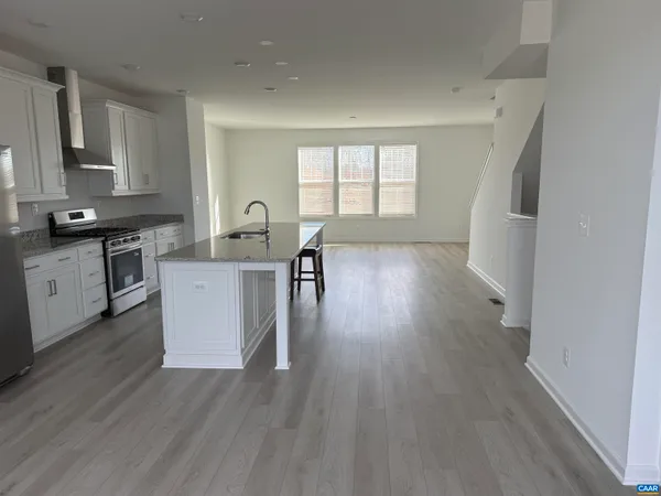 a kitchen with granite countertop a stove a sink dishwasher and a refrigerator with wooden floor