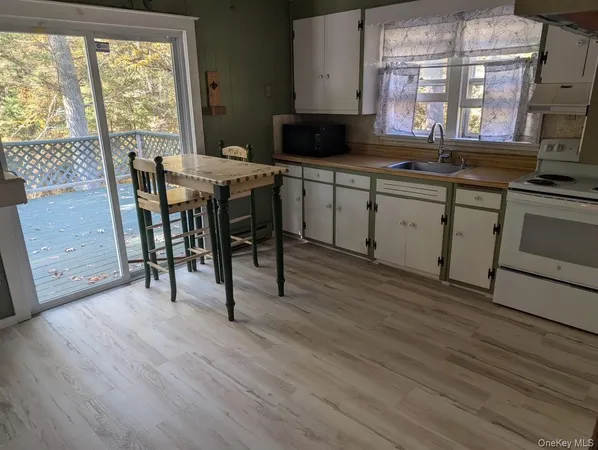 a kitchen with a sink a stove cabinets and wooden floor
