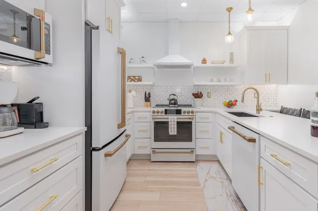 a kitchen with white cabinets and appliances