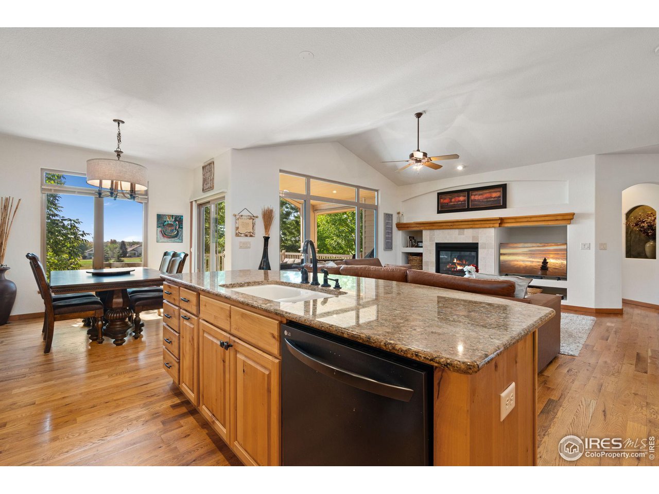 6747 Spanish Bay Drive Windsor, CO 80550 - Photo 10 of 30 a kitchen with kitchen island granite countertop a stove a sink a dining table and chairs with wooden floor