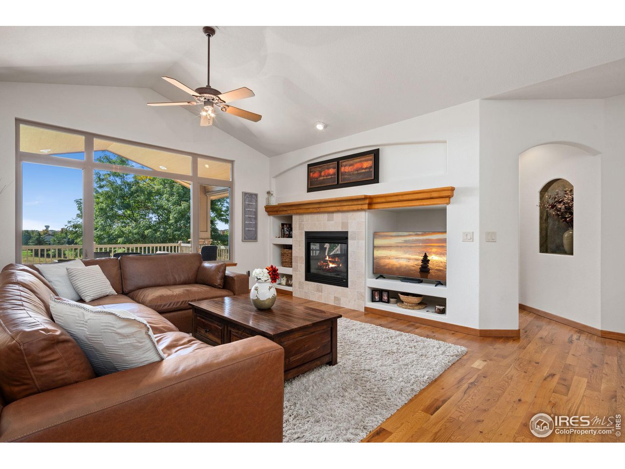 6747 Spanish Bay Drive Windsor, CO 80550 - Photo 7 of 30 a living room with furniture a fireplace and a flat screen tv