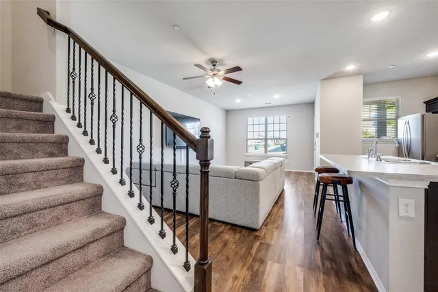 a living room with couches painting on wall with wooden floor and dining room view