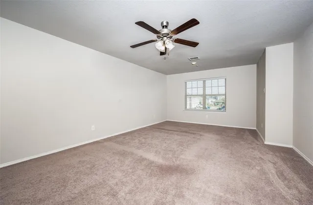an empty room with windows and fan