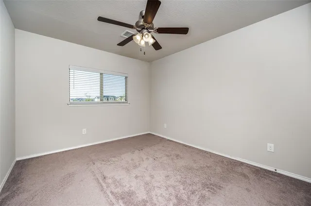 an empty room with a chandelier fan and windows