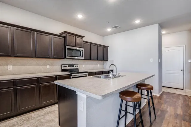 a kitchen with a sink a stove a refrigerator cabinets and a chairs