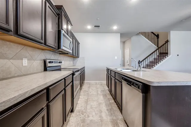 a kitchen with stainless steel appliances granite countertop a sink a stove and a wooden floors