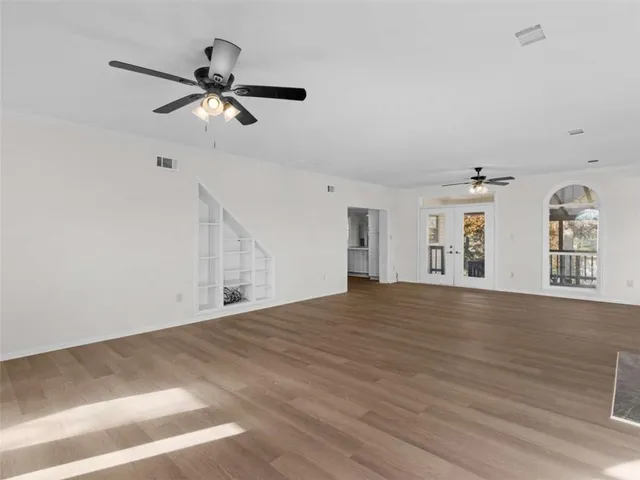 a view of a livingroom with a ceiling fan window and wooden floor