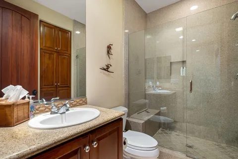 a bathroom with a granite countertop sink toilet a mirror and shower