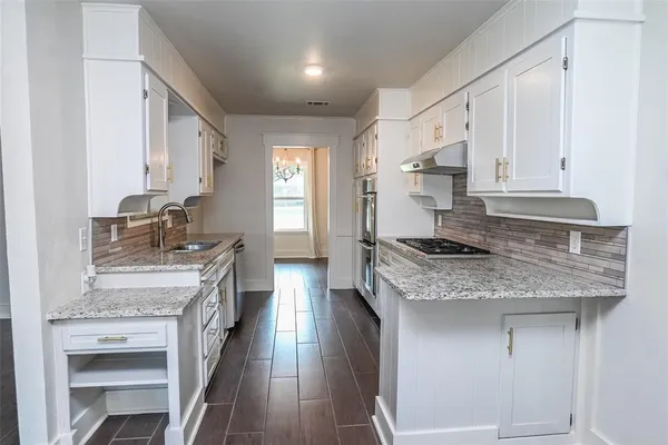 a kitchen with a stove sink and cabinets