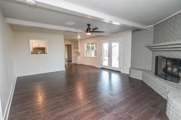 an empty room with wooden floor fireplace and windows