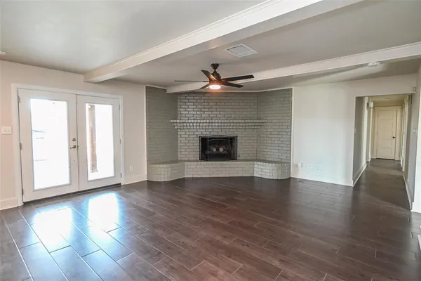 an empty room with wooden floor fireplace and windows