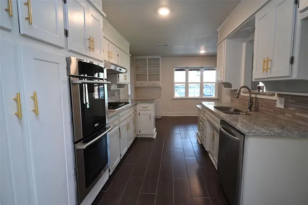 a kitchen with stainless steel appliances granite countertop a refrigerator a sink dishwasher a stove and white countertops with wooden floor