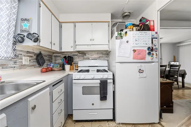 a kitchen with white cabinets sink and stove