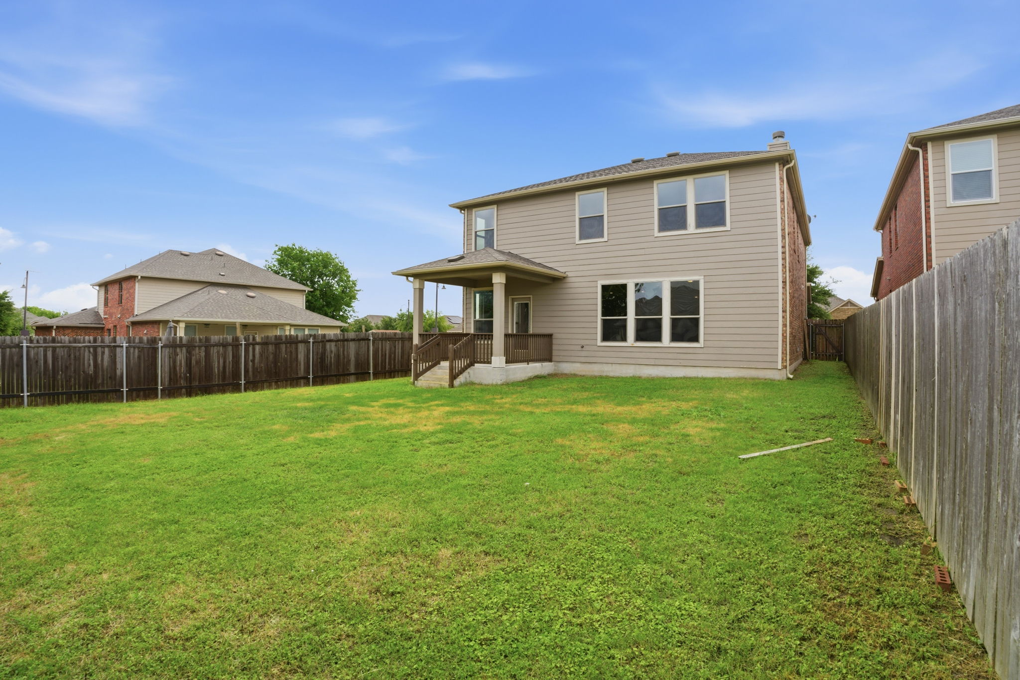 670 Landon Samuel Loop Pflugerville, TX 78660 - Photo 21 of 22 Expansive fenced backyard featuring a covered patio, tan siding, and multiple windows