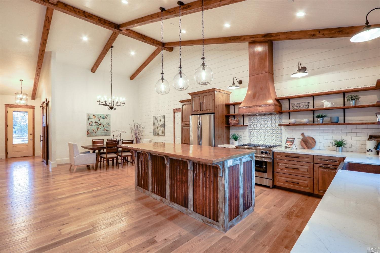 a large kitchen with stainless steel appliances a stove and wooden floor