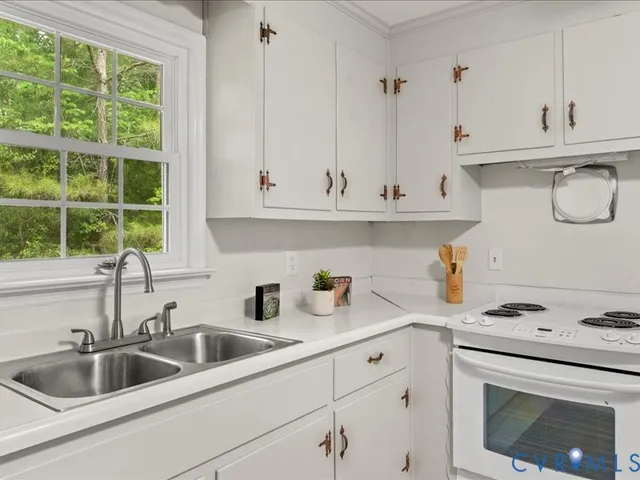 a kitchen with white cabinets and sink