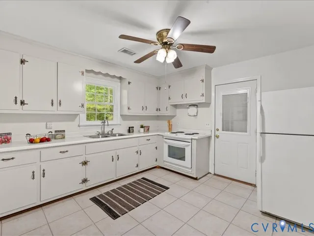 a kitchen with white cabinets appliances and a window