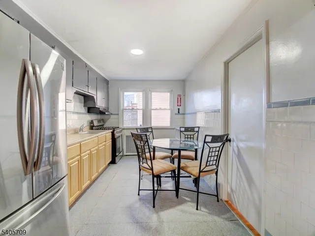 a kitchen with stainless steel appliances a refrigerator a stove a sink dishwasher a dining table and chairs with wooden floor