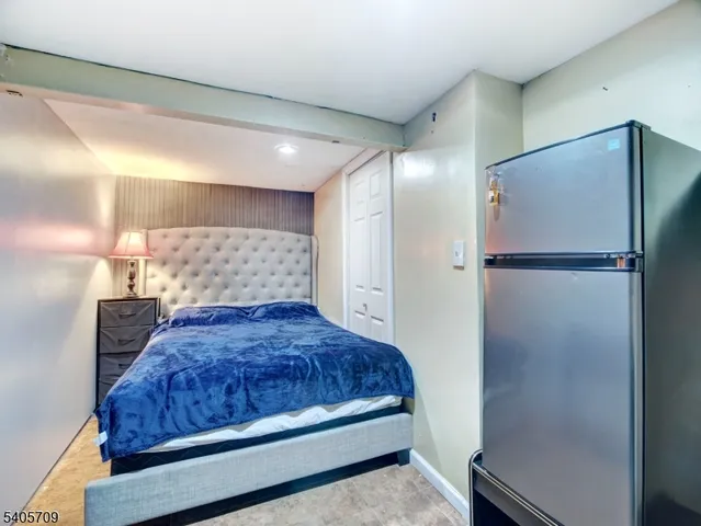 a bedroom with a bed and a refrigerator