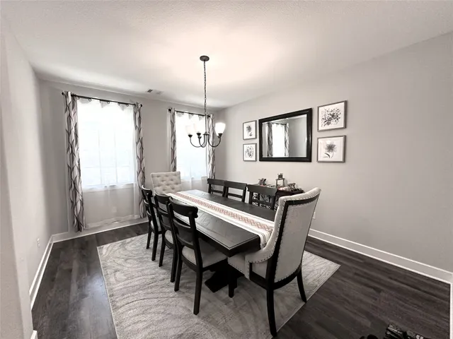 a large living room with stainless steel appliances kitchen island granite countertop a refrigerator a stove a sink dishwasher and a dining table with wooden floor